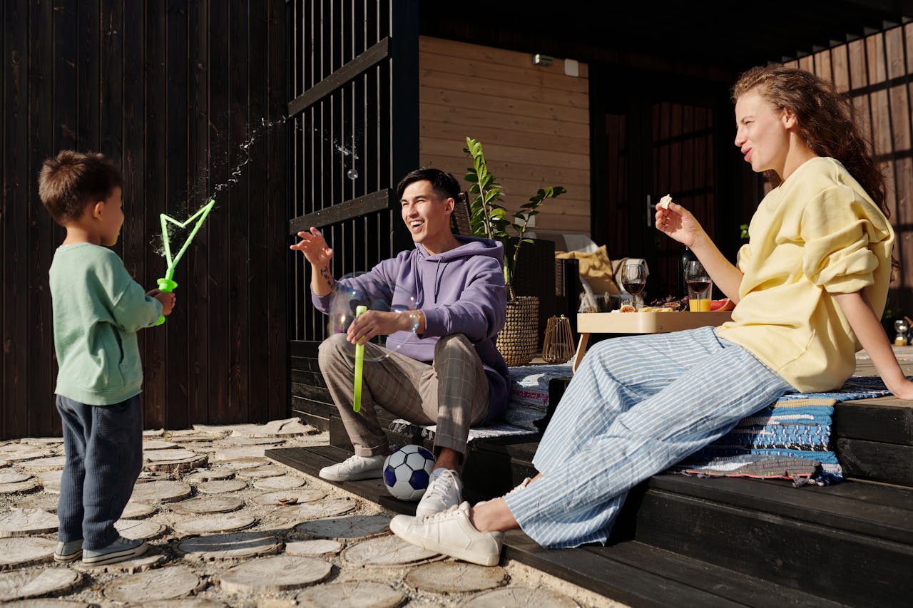 A family spends quality time playing with bubbles outside on a sunny day.